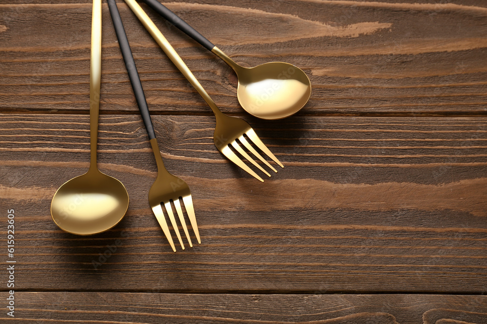 Golden forks and spoons on wooden background