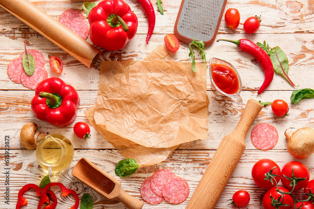 Different ingredients for preparing pizza and parchment on light wooden background