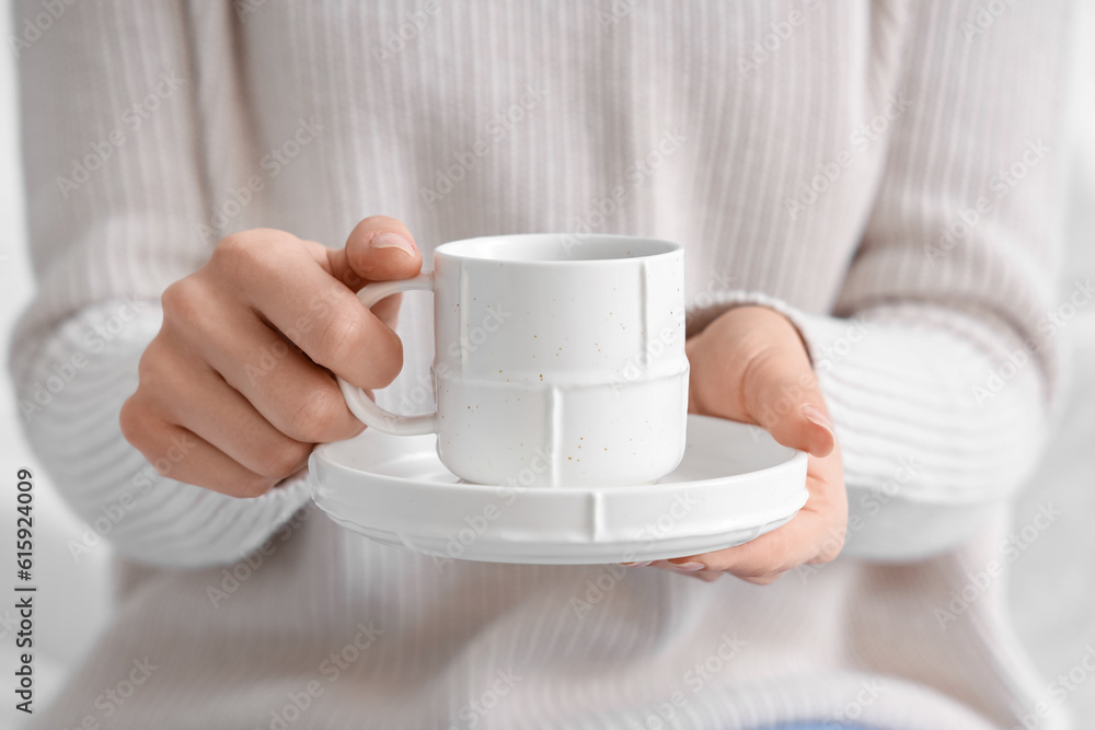 Woman holding saucer with cup of coffee, closeup