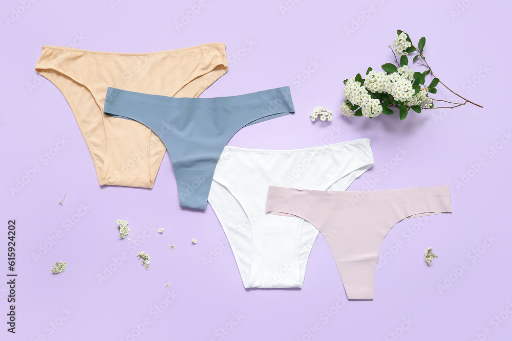 Set of stylish female panties and blooming plant branch on color background