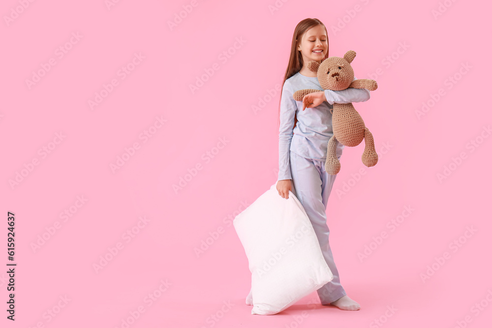 Little girl with pillow and toy on pink background