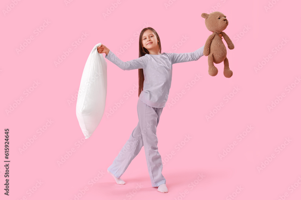 Little girl with pillow and toy on pink background