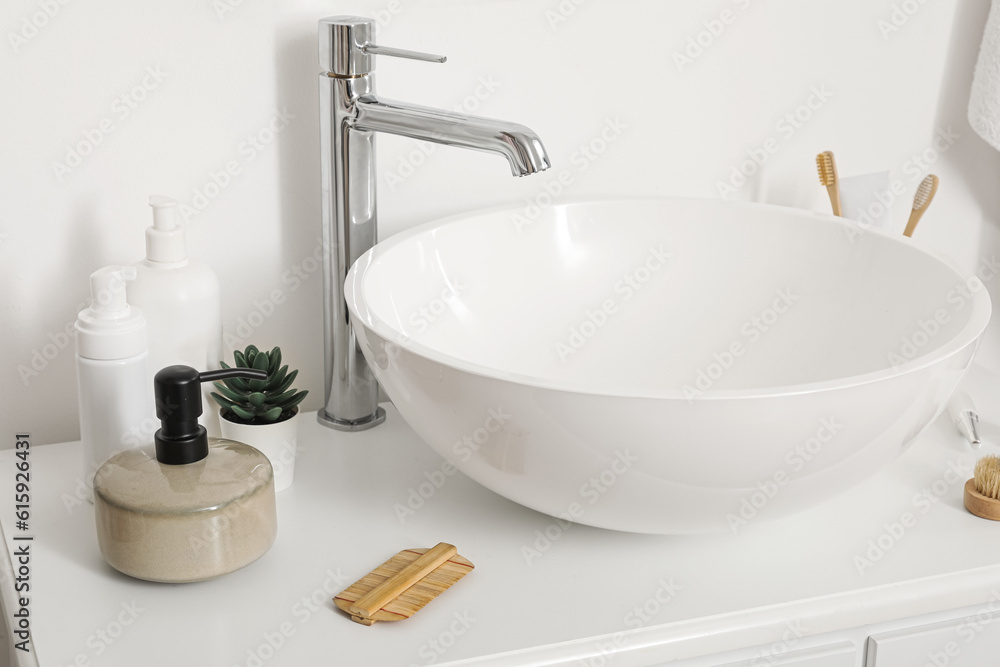 Sink bowl with bath accessories on table in bathroom