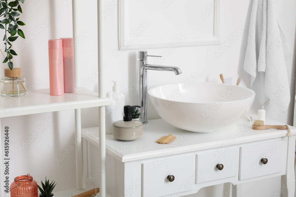 Sink bowl with bath accessories on table in bathroom