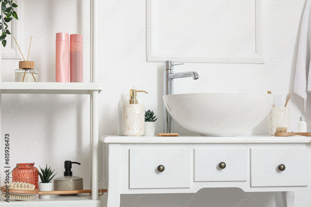 Sink bowl with bath accessories on table in bathroom