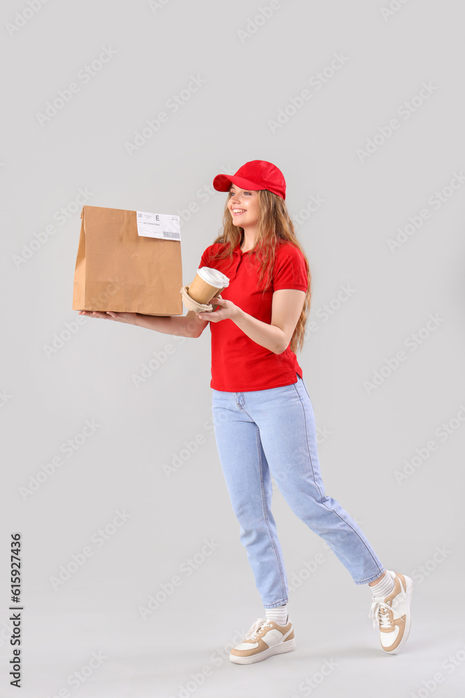 Female courier with food on grey background