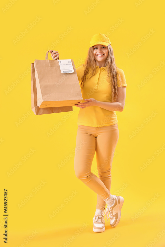 Female courier with paper bags on yellow background