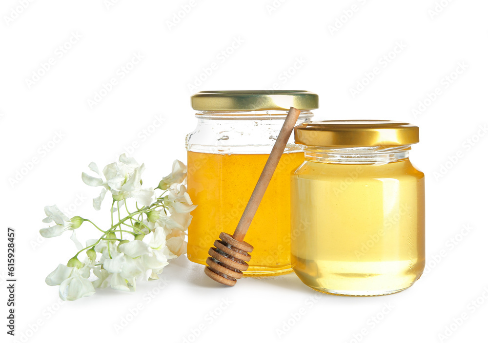 Jars of honey with flowers of acacia and dipper on white background