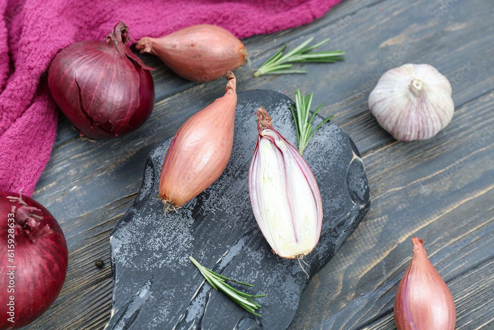 Slate board with garlic and onion on dark wooden background, closeup