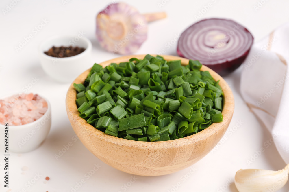 Bowl with slices of fresh scallion and onion on white background