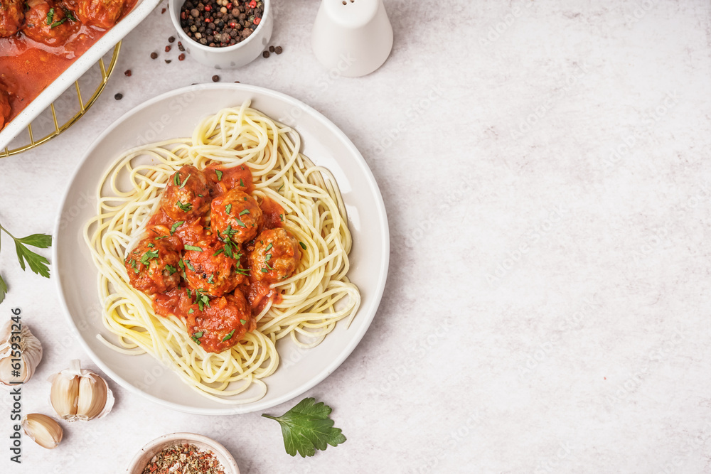 Plate of boiled pasta with tomato sauce and meat balls on white table