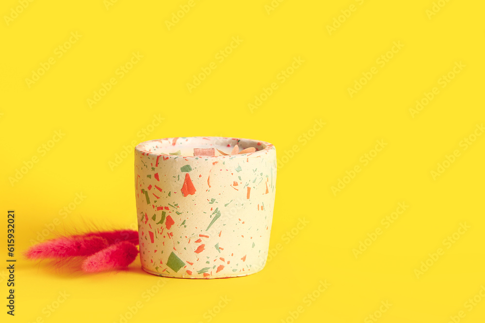 Holder with candle and lagurus on yellow background