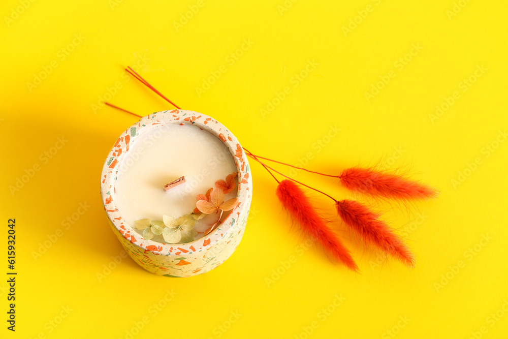 Holder with candle and lagurus on yellow background