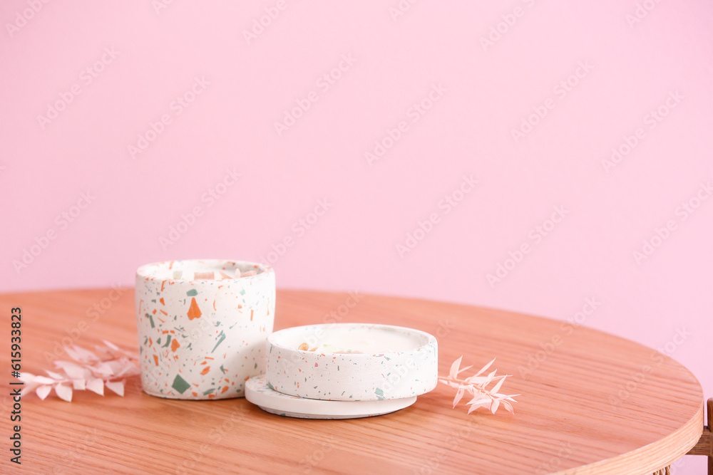 Holders with candles on table near pink wall in room