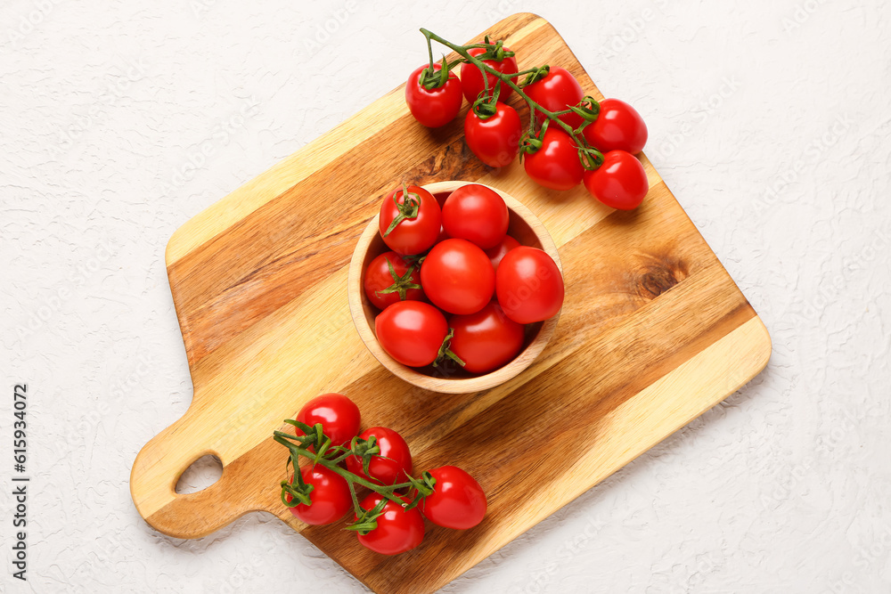 Board and bowl with fresh cherry tomatoes on white background