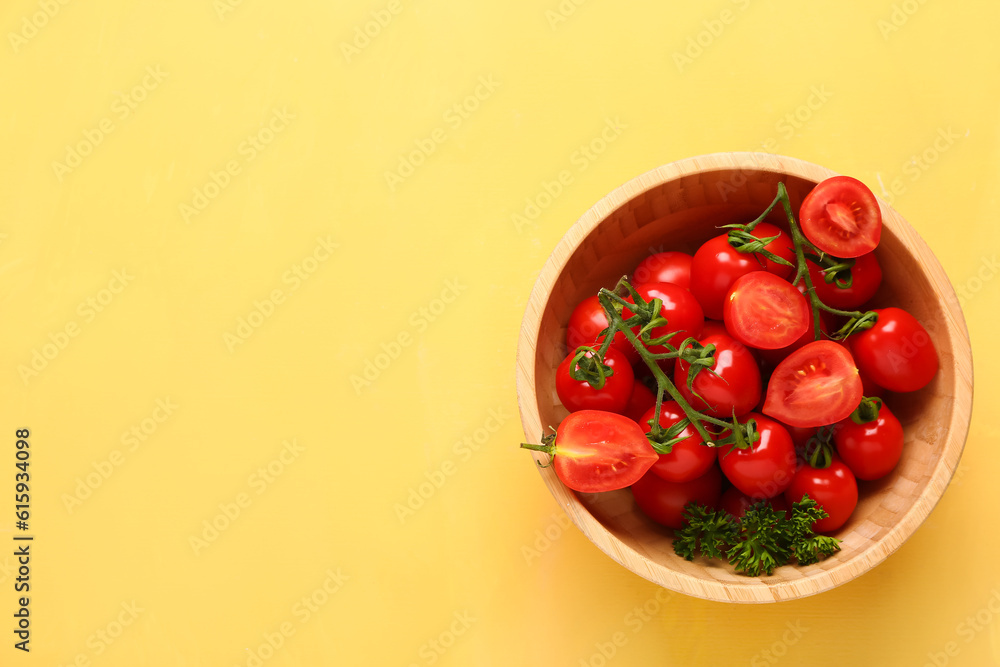 Wooden bowl with fresh cherry tomatoes and parsley on yellow background