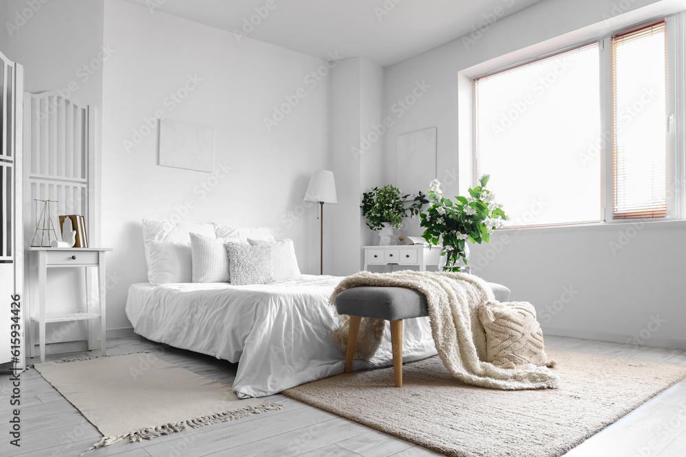 Interior of light bedroom decorated with blooming jasmine flowers in vase