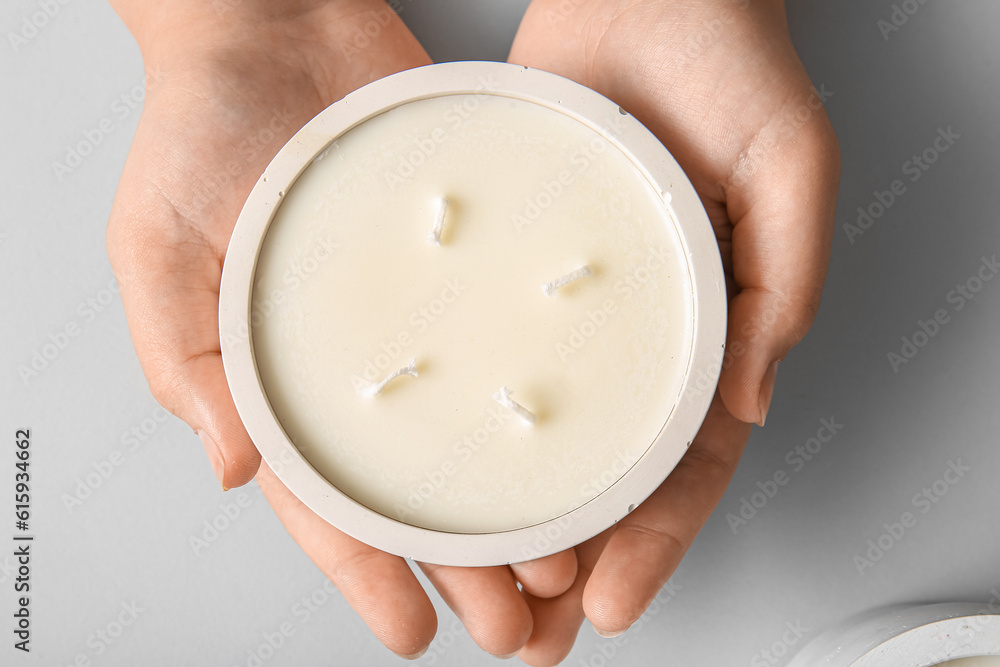 Female hands with candle on light background, closeup