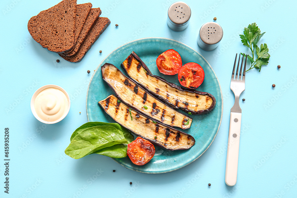 Plate with delicious grilled eggplants, tomatoes, sauce and bread on light blue background