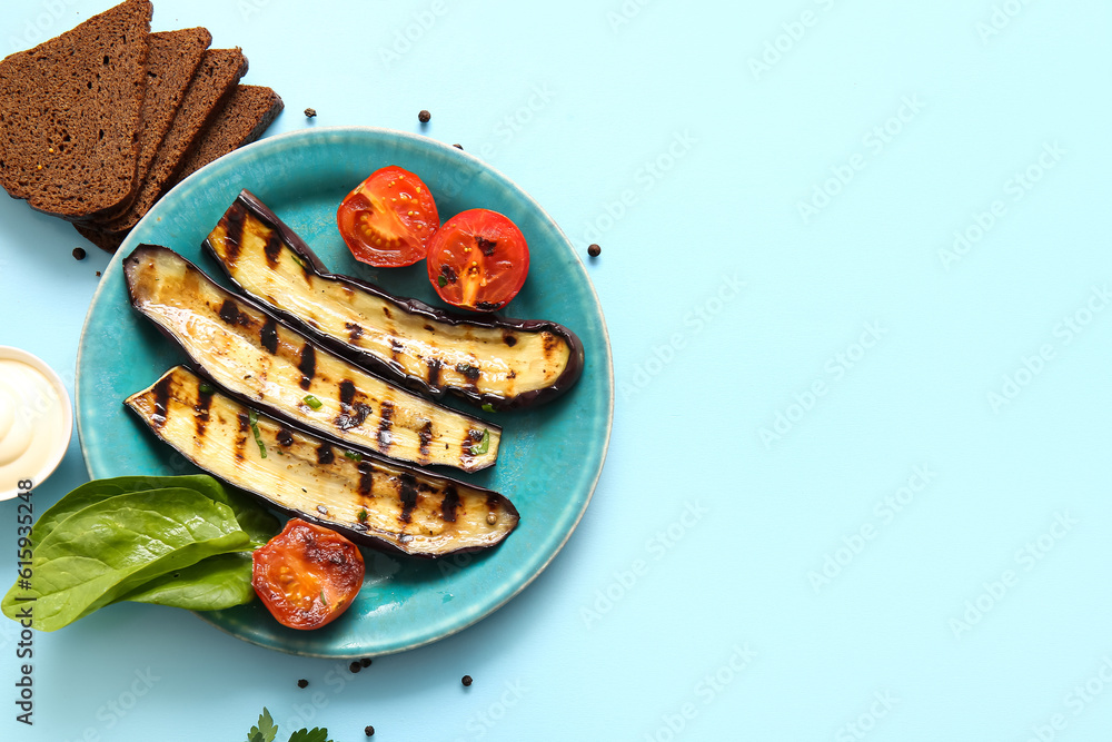 Plate with delicious grilled eggplants, tomatoes and bread on light blue background