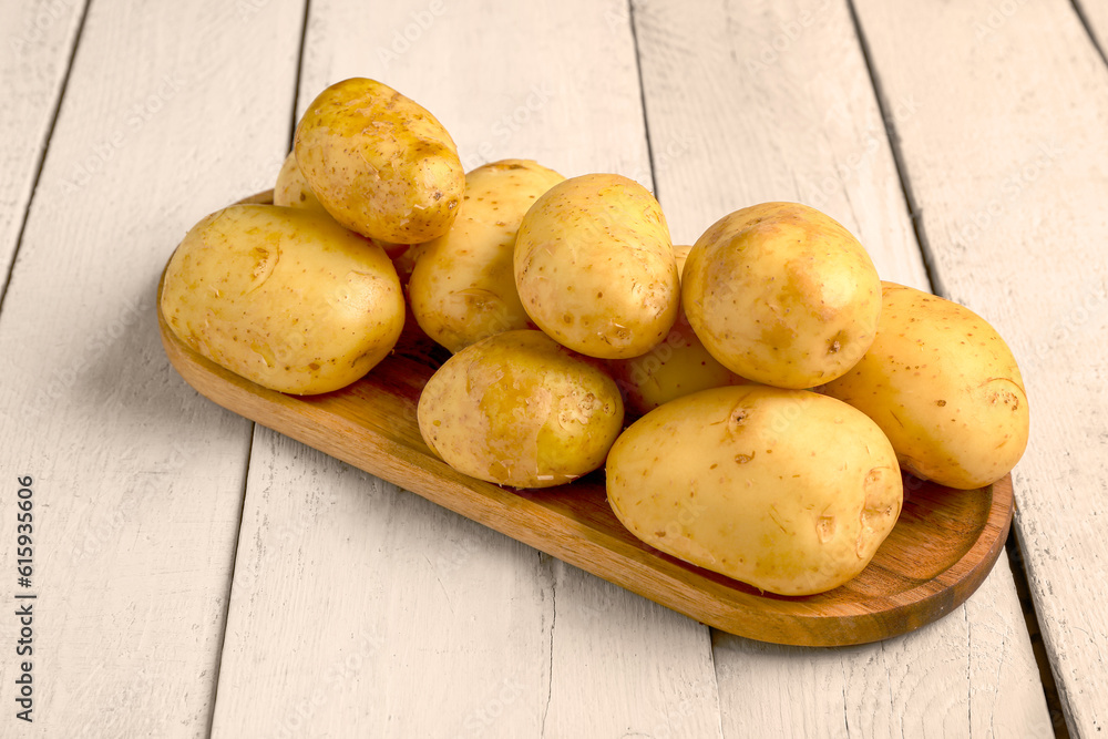 Tray with raw baby potatoes on white wooden background