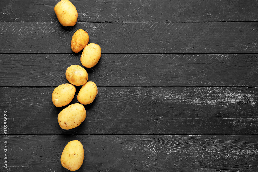 Raw baby potatoes on black wooden background