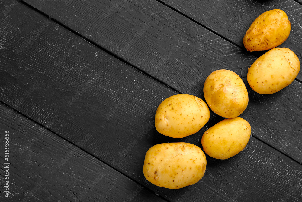 Raw baby potatoes on black wooden background