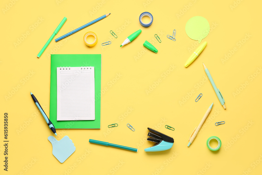 Notebooks with frame made of different stationery on yellow background