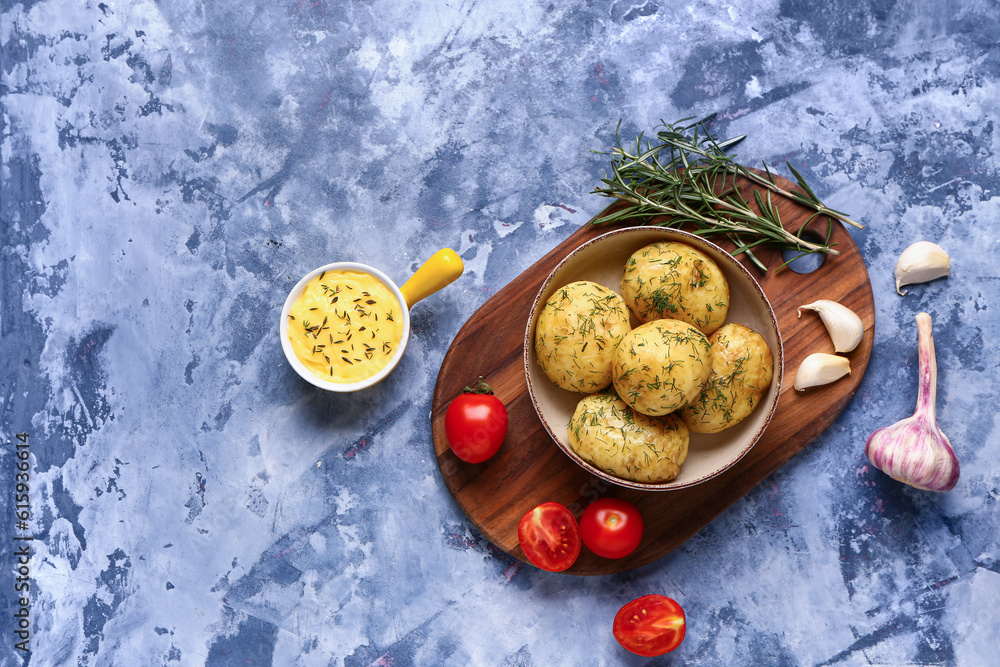 Bowl of boiled baby potatoes with dill and tomatoes on blue background