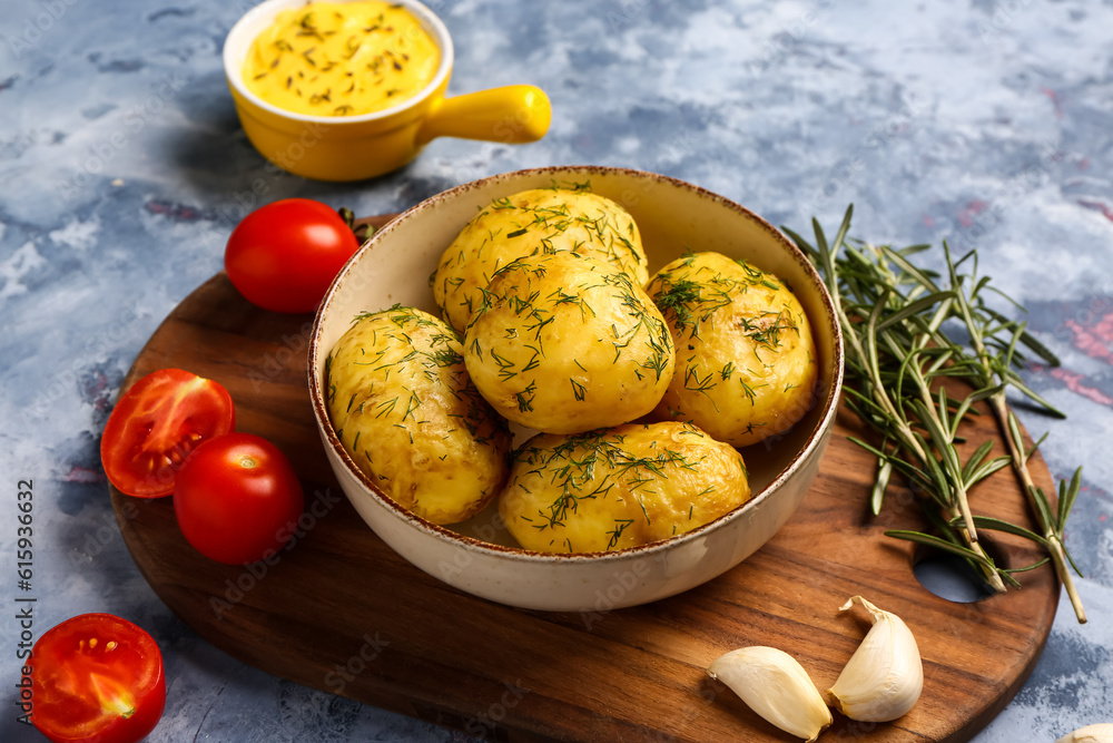 Bowl of boiled baby potatoes with dill and tomatoes on blue background