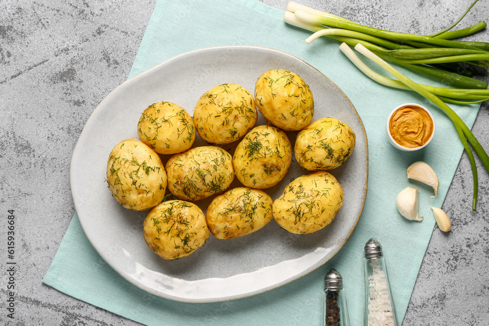 Plate of boiled baby potatoes with dill and mustard on grey background