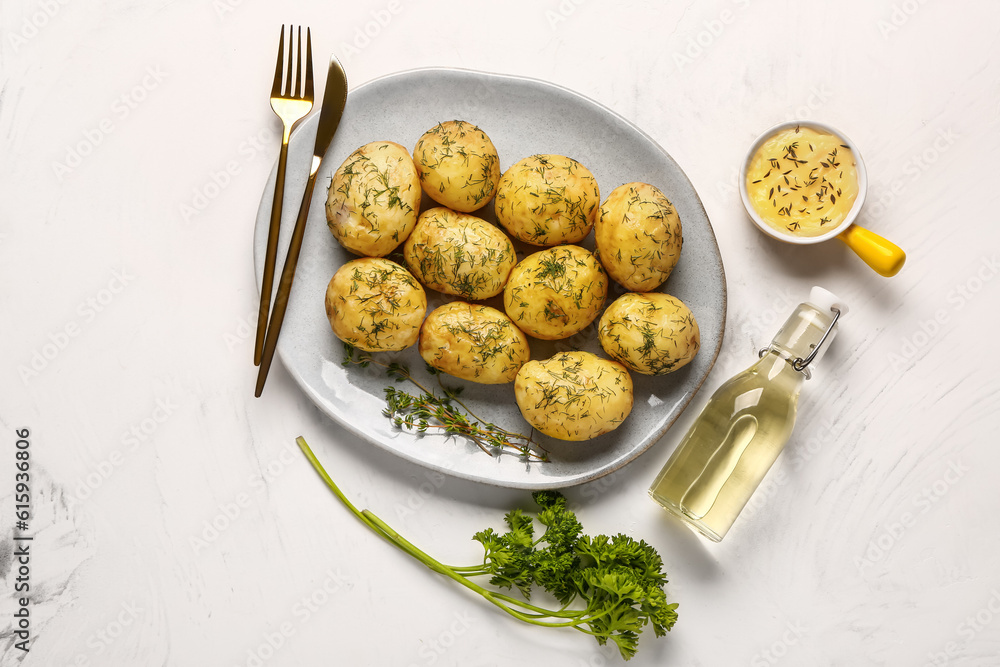 Plate of boiled baby potatoes with dill and sauce on white background