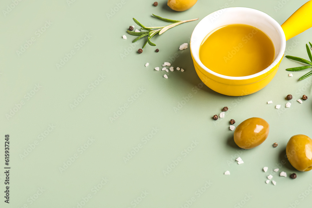 Bowl with fresh olive oil on green background