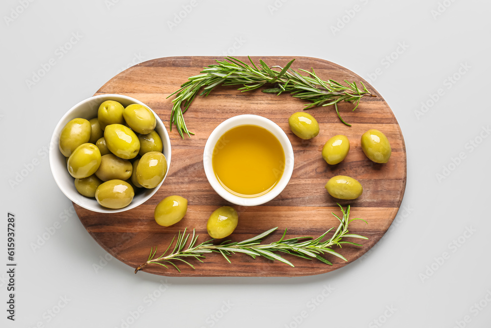 Bowls with ripe olives and oil on grey background