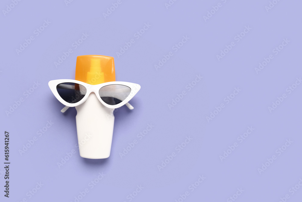 Creative composition with sunglasses and bottle of sunscreen cream on lilac background