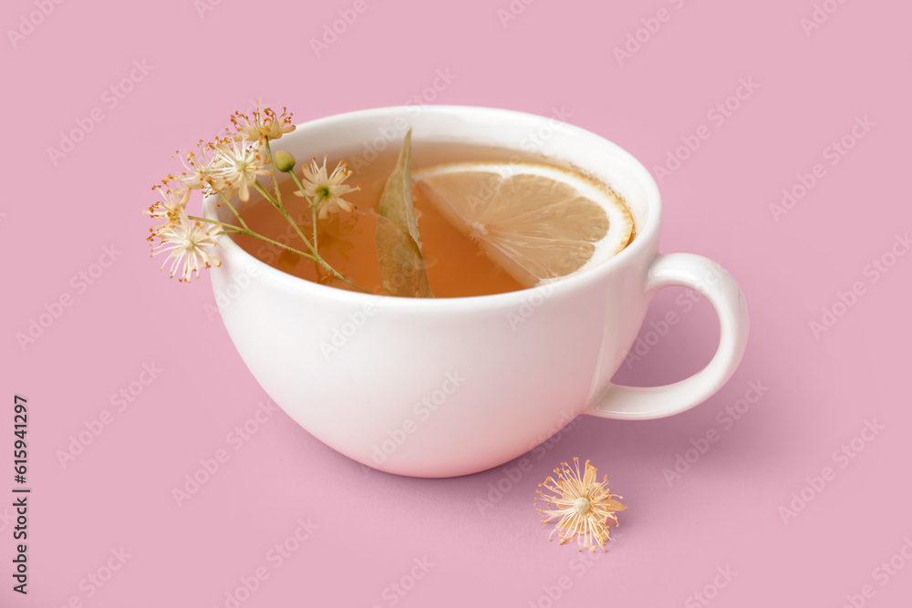 Cup of linden tea with lemon on pink background