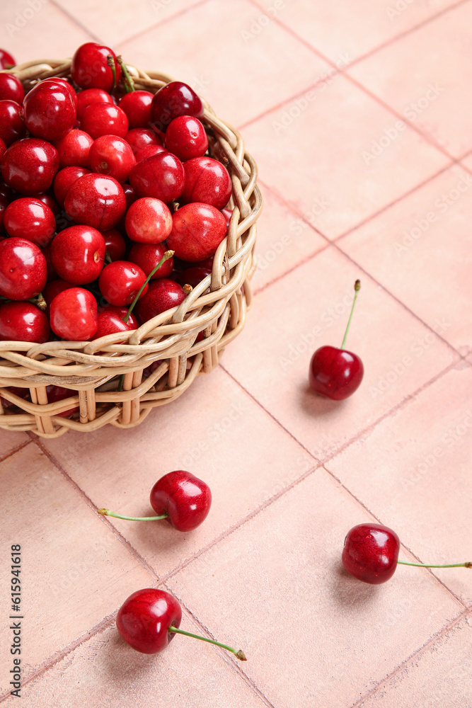 Wicker bowl with sweet cherries on pink tile background