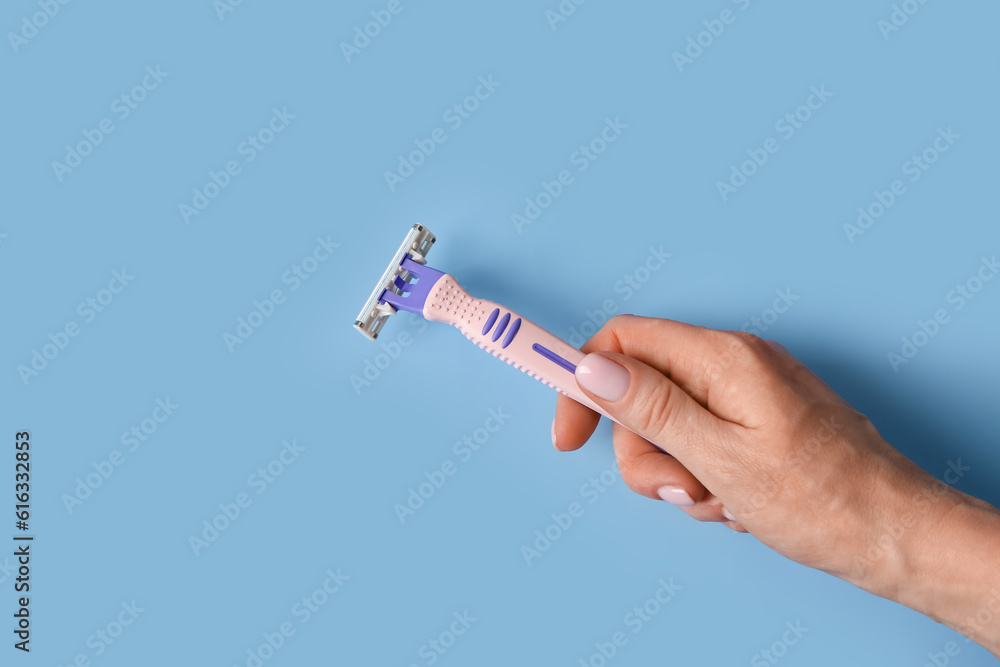 Female hand with safety razor on color background, closeup