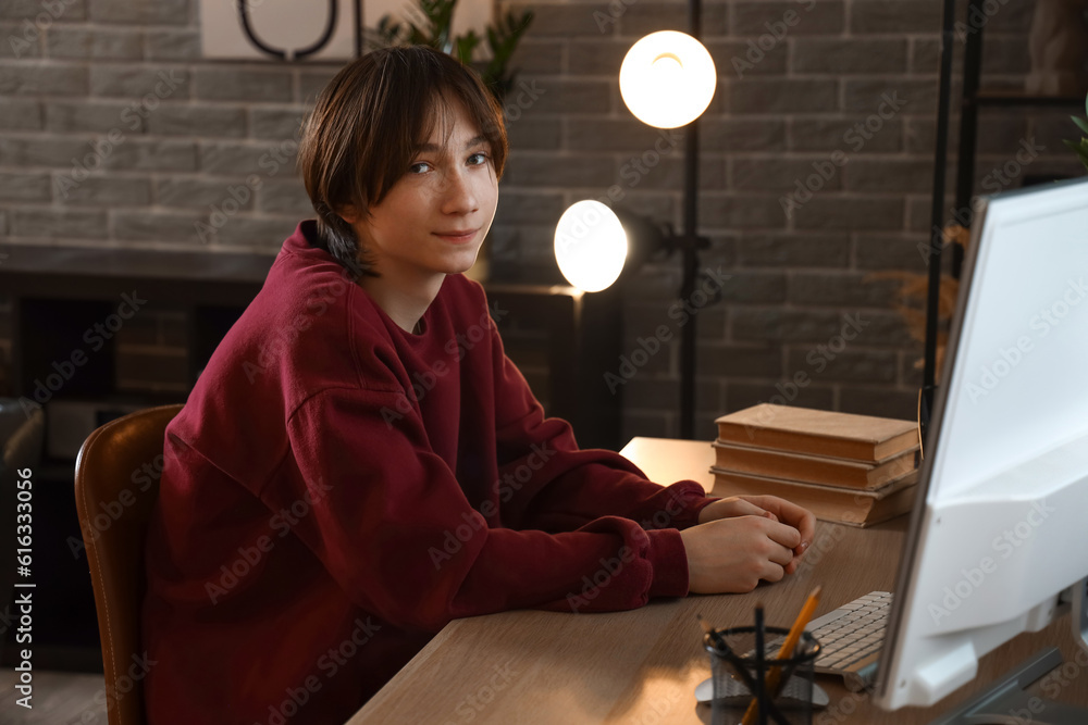 Teenage boy with books sitting at table late in evening