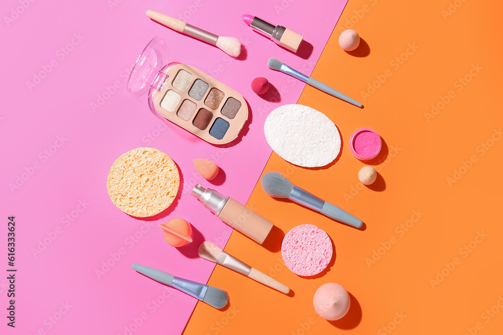 Decorative cosmetics with makeup brushes and sponges on color background