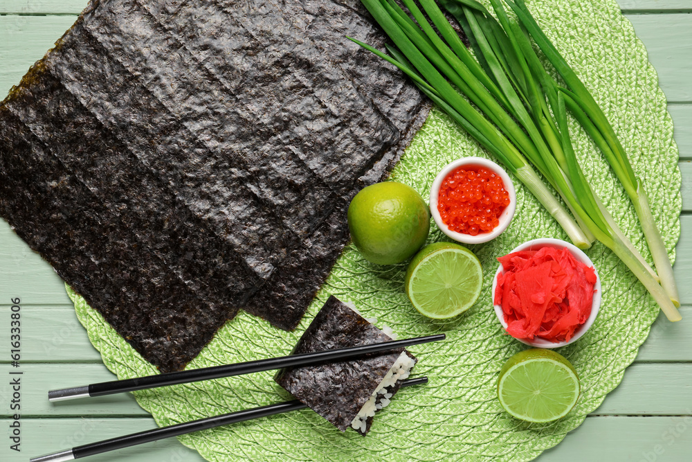 Nori sheets, caviar, ginger and lime on green wooden background