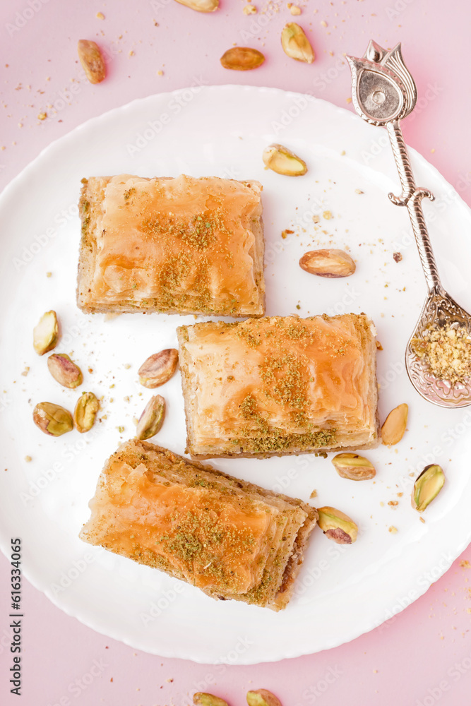 Plate with tasty baklava on pink background, closeup