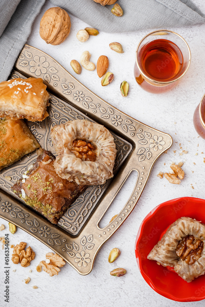 Tray with tasty baklava and glass of Turkish tea on light background