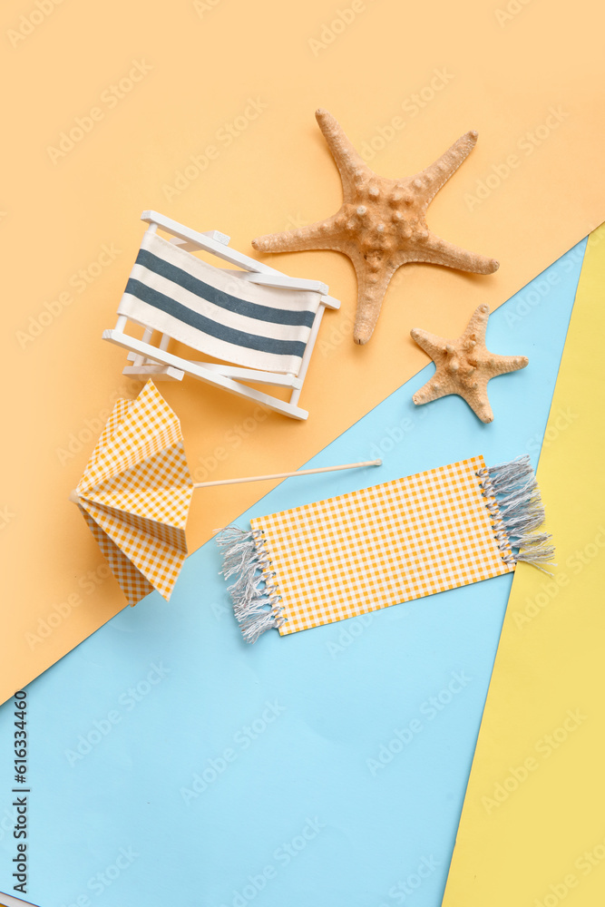 Composition with miniature deck chair, starfishes and paper umbrella on colorful background