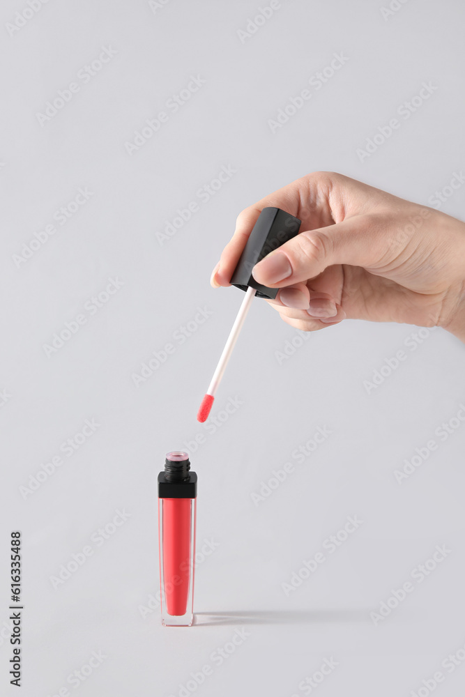 Female hand and lip gloss on white background