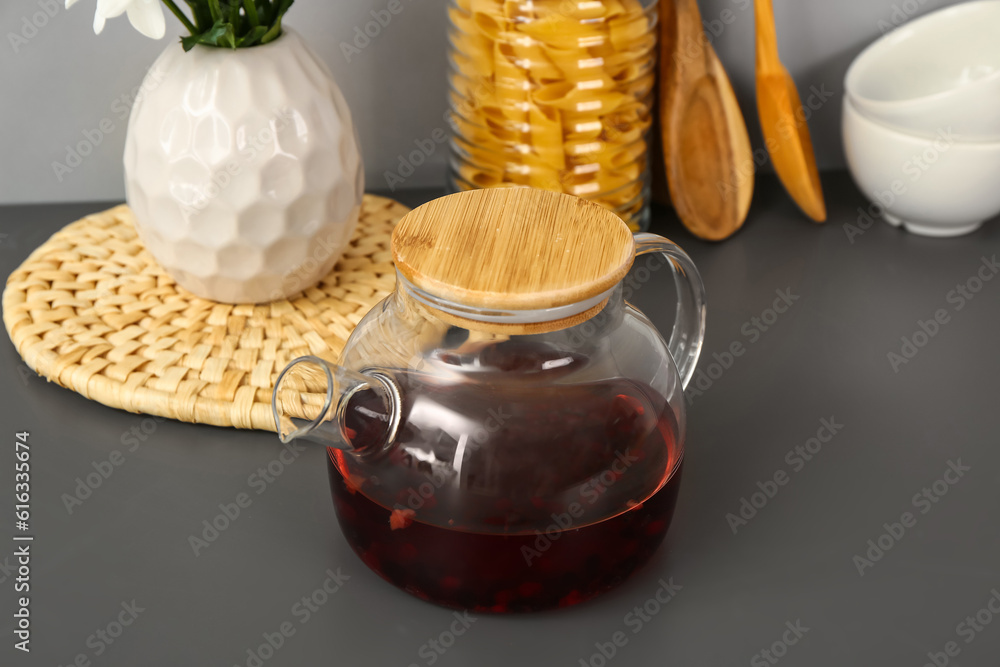 Teapot with cups and different kitchen stuff on black table