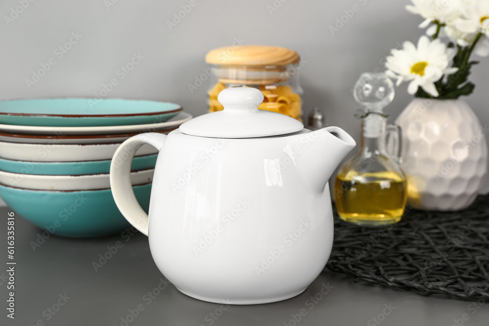 Teapot with flowers and different kitchen stuff on black table