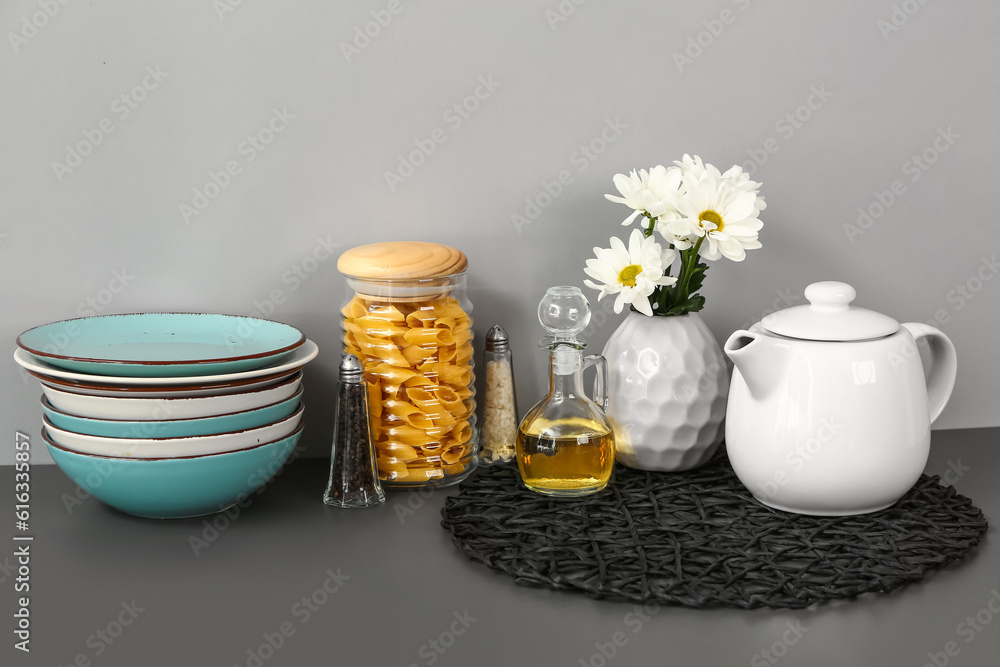 Teapot with flowers and different kitchen stuff on black table