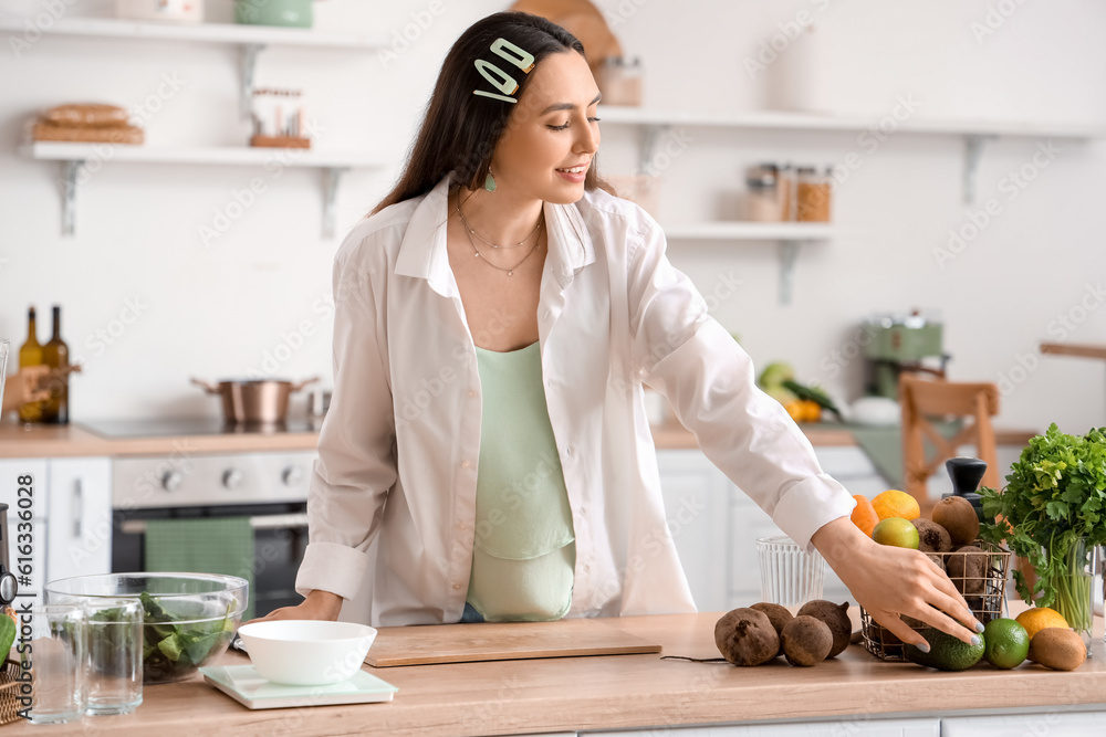 Young woman making vegetable juice in kitchen