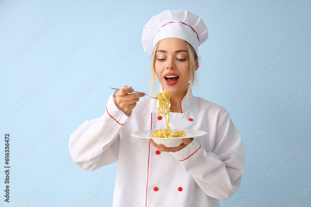 Female chef eating tasty pasta on blue background